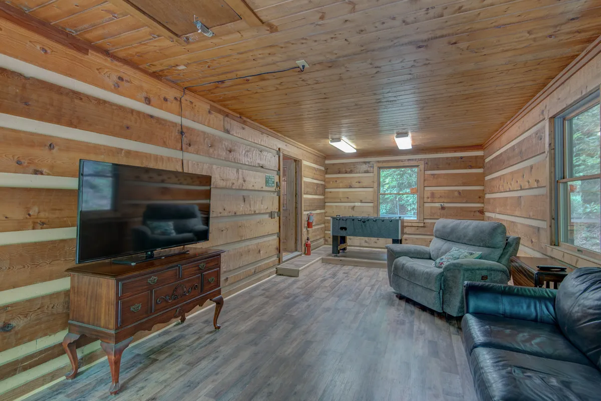 This image captures the recreation room with a foosball table, cozy sofa, television, and warm wooden walls. The inviting room is designed for indoor fun and social gatherings, with space for friendly competition and family relaxation.